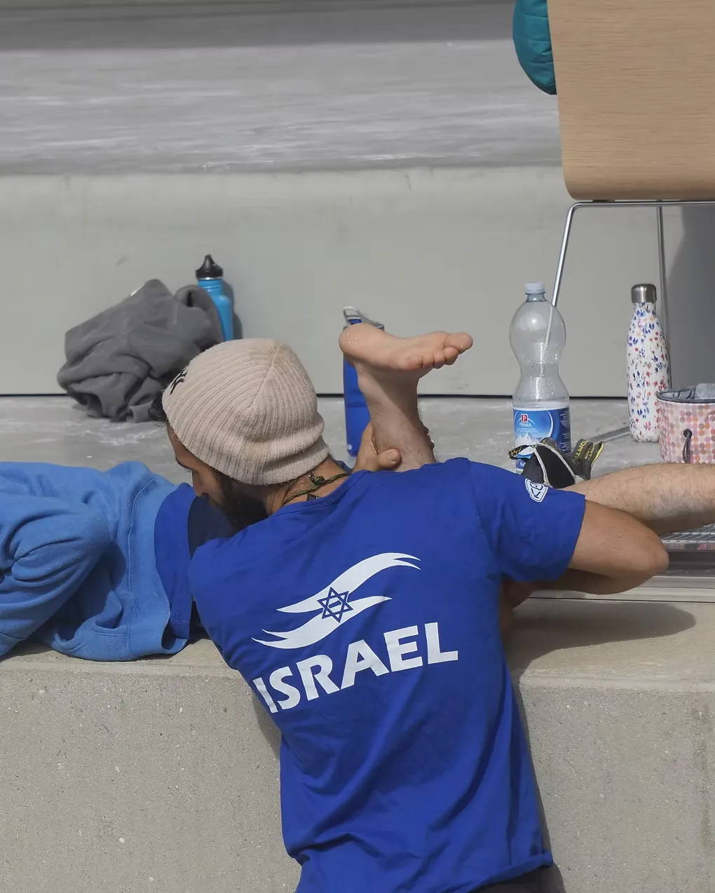 רועי מטפל ברגל של ספורטאי ששוכב על ספסל בתחרות